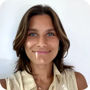 Portrait of Valentina, a smiling woman with shoulder-length brown hair in a sleeveless cream top