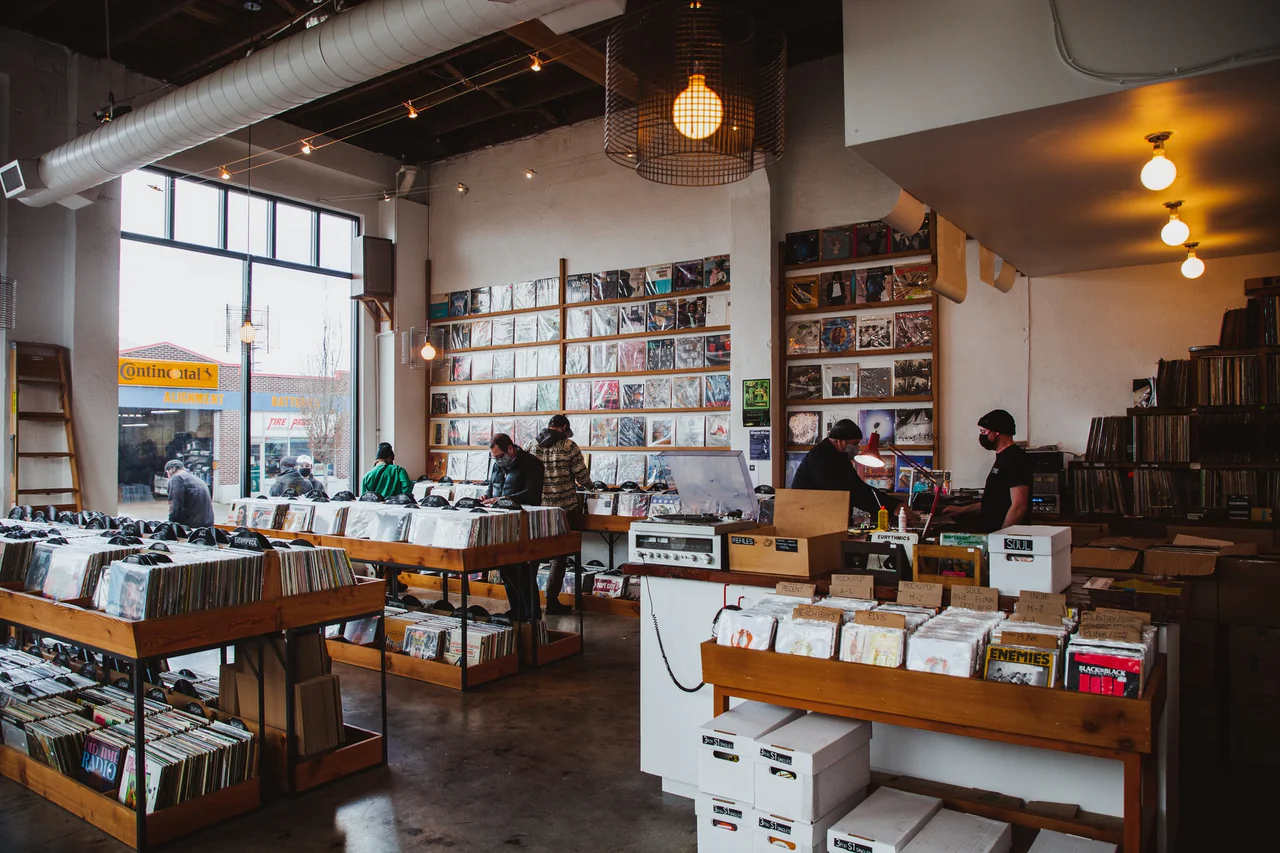 Record shop interior with shoppers flipping through crates of vinyl and albums lining the wall
