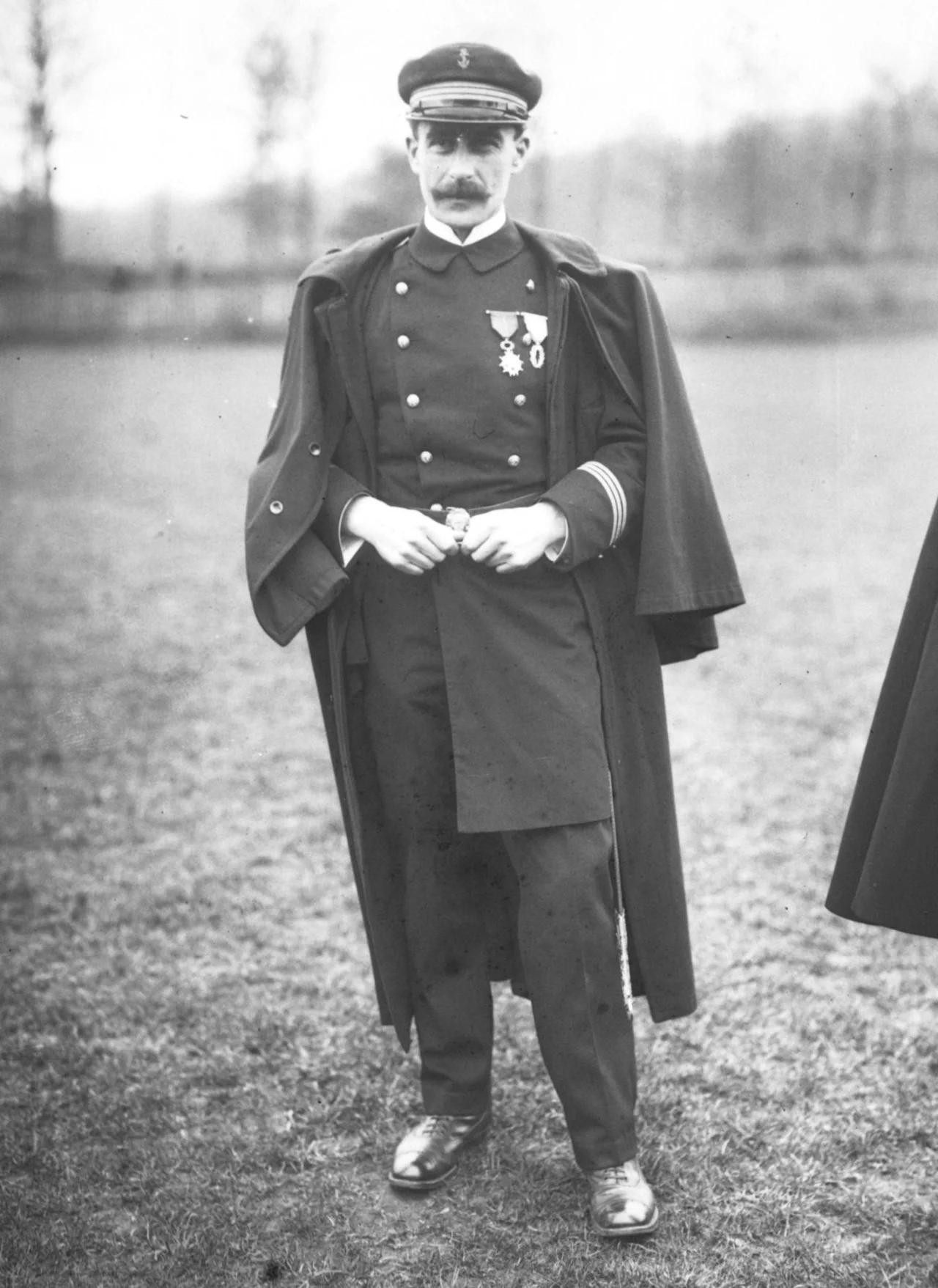 Black-and-white portrait of a mustached naval officer in uniform and cape, with medals on his chest