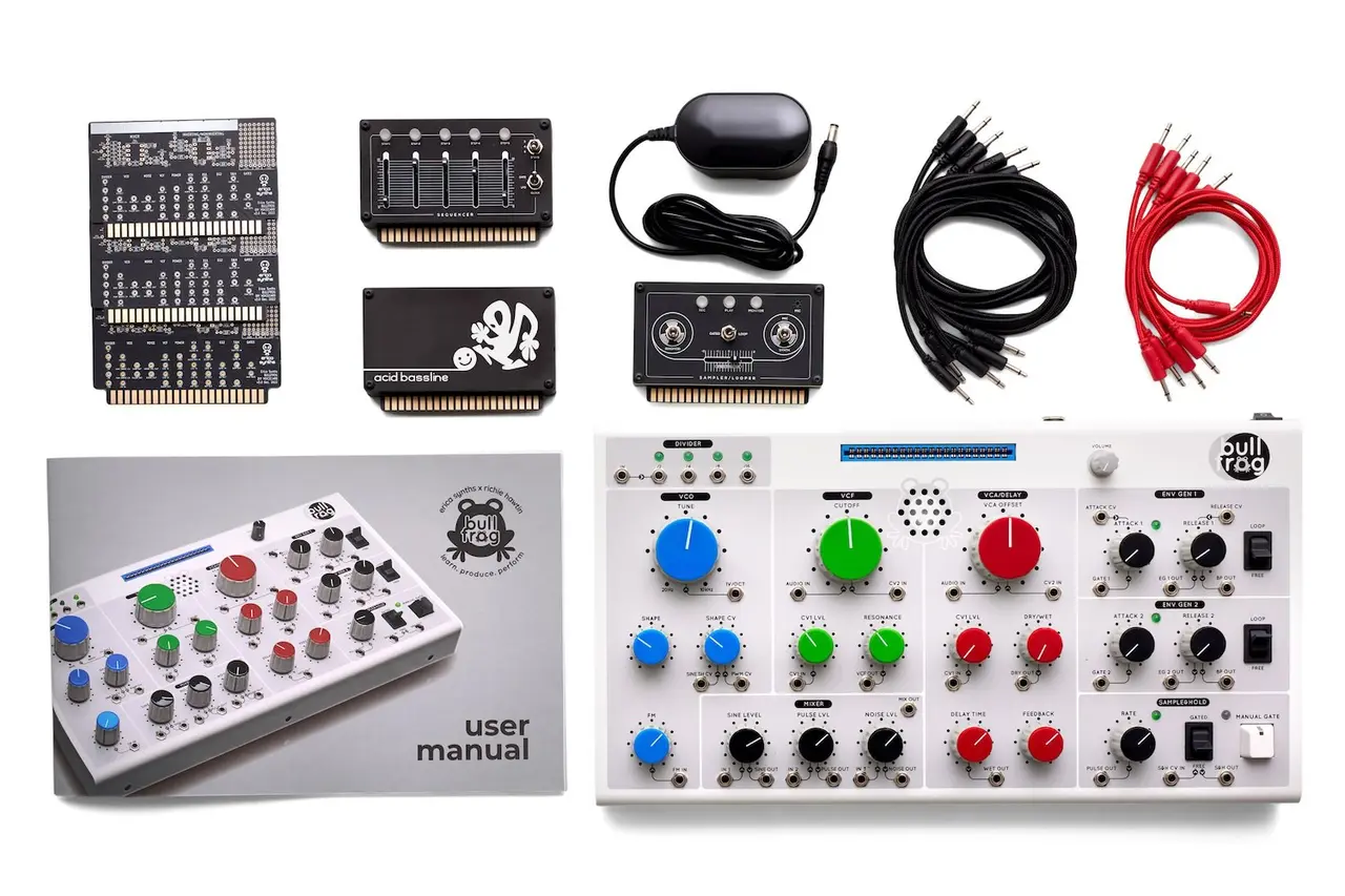 Bullfrog synth kit laid out flat: the synth, plug-in voice cards, power adapter, patch cables and user manual