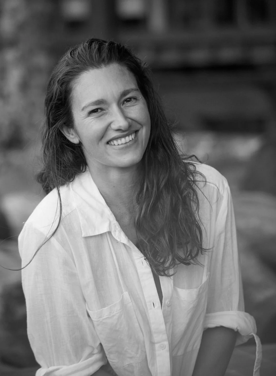 Black-and-white portrait of a smiling woman in a white shirt, the person quoted below